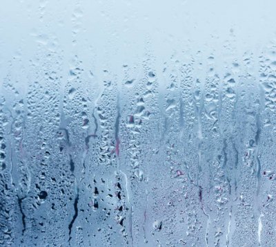 Window glass with condensation, strong, high humidity in the room, large water droplets flow down the window, cold tone, natural water drops on window