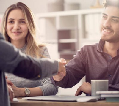 Young couple shaking hands with a female agent