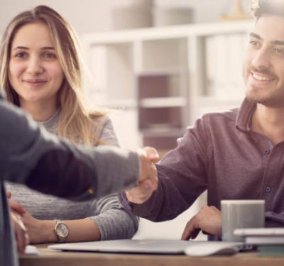 Young couple shaking hands with a female agent